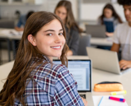 High school student smiling facing camera using laptop